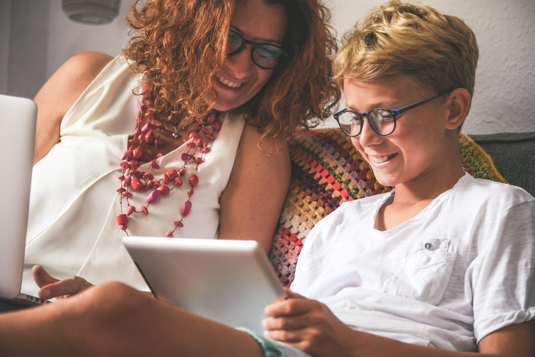 Un ado et sa maman qui regardent une tablette en souriant