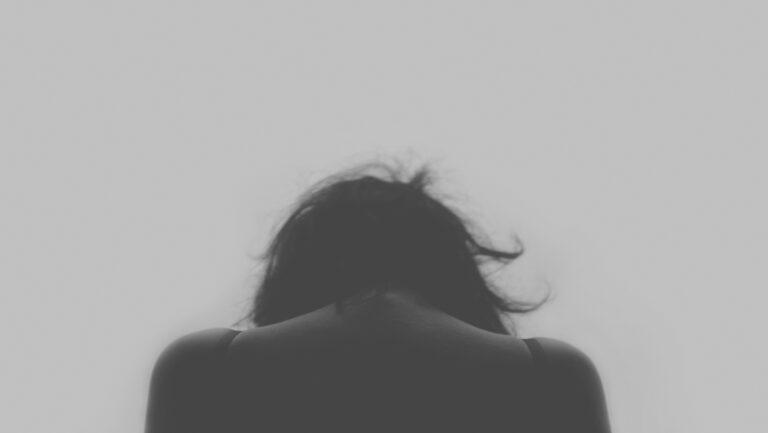 Jeune de dos la tête baissée, image en noir et blanc.