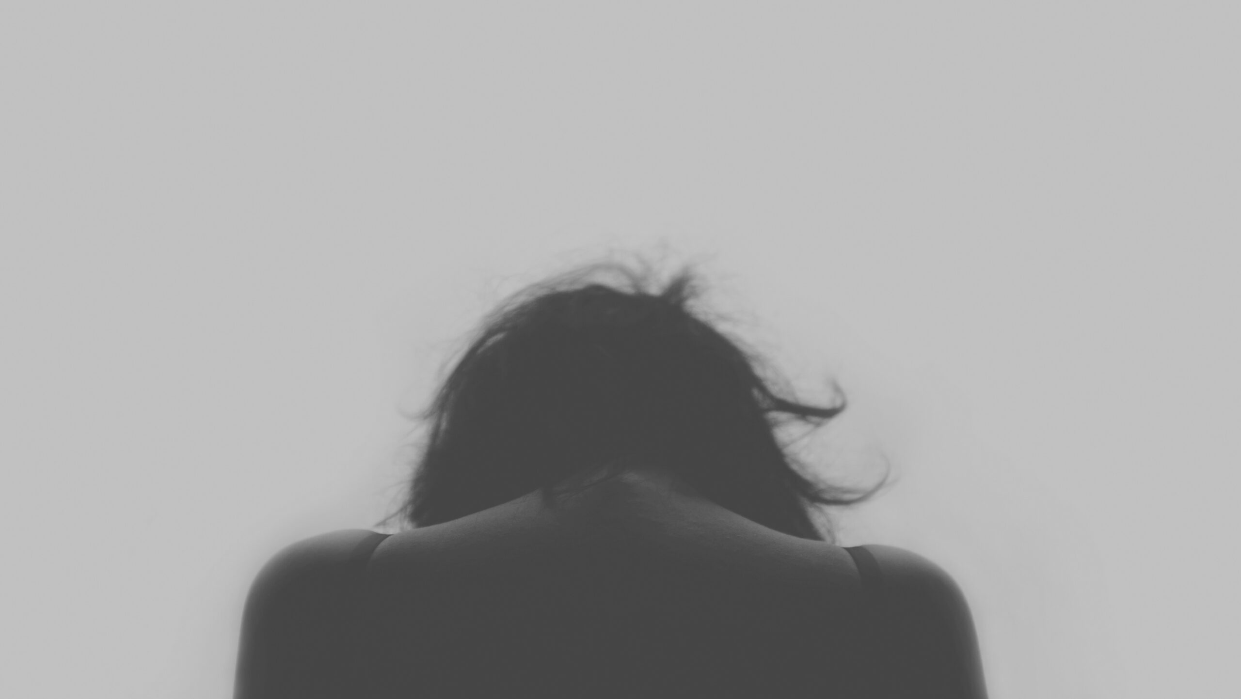 Jeune de dos la tête baissée, image en noir et blanc.