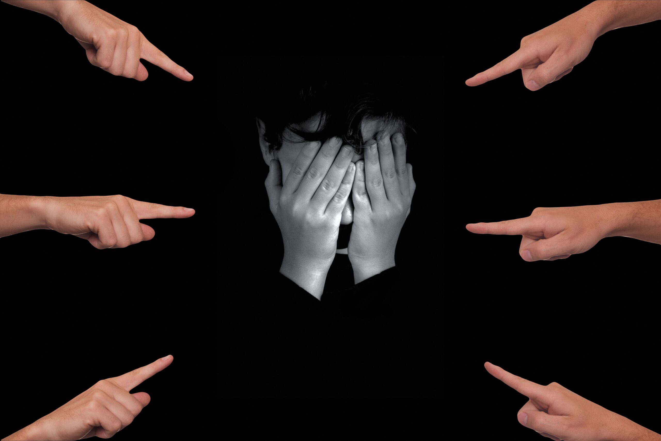 Enfant en noir et blanc la tête dans les mains, qui a des doigts pointés sur lui