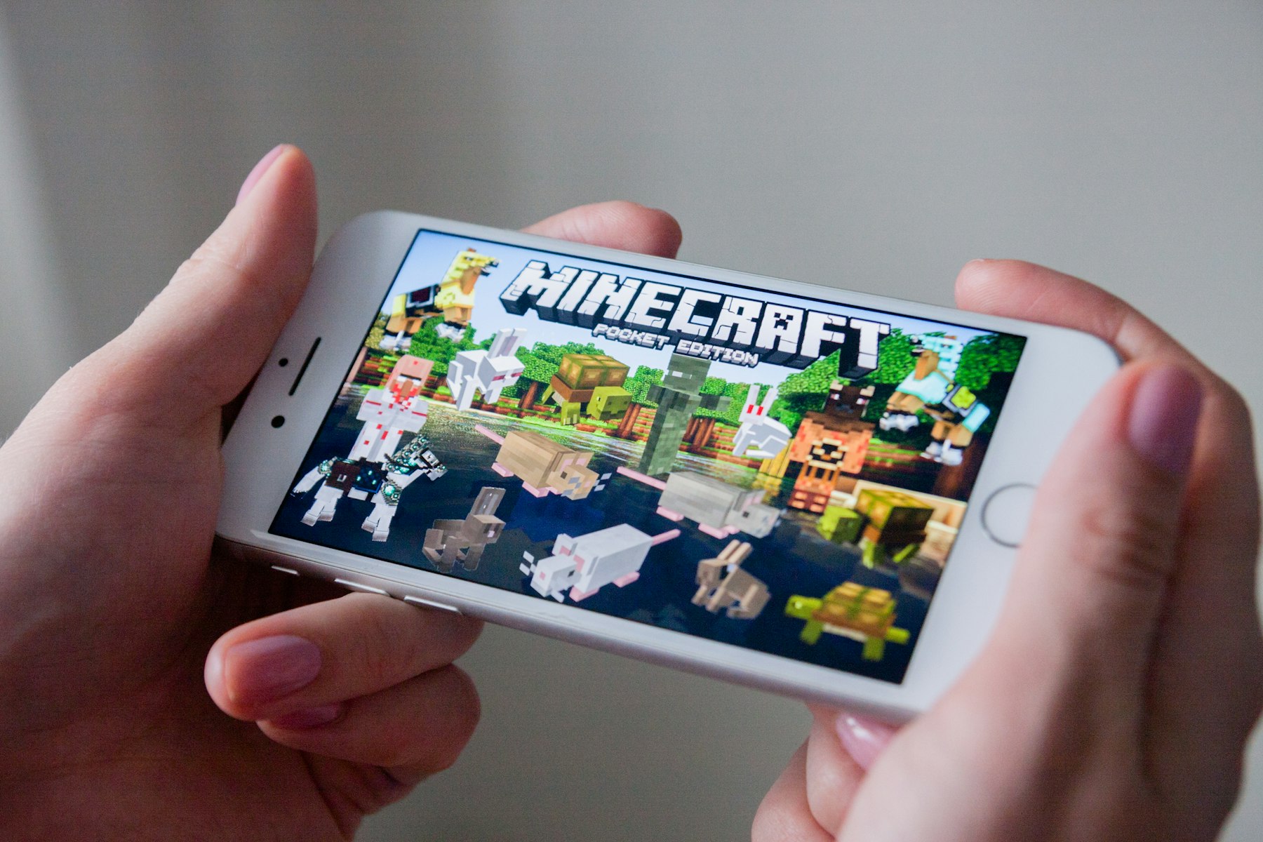 Image d'un jeune qui tient son téléphone avec Minecraft dessus
